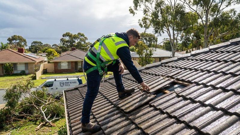 Professional roofer securing loose tiles and performing emergency repairs after a severe Perth winter storm